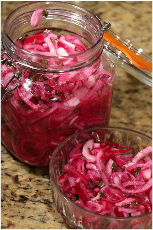 Red pickled onions in a glass jar and bowl. Credit to Nigel Cohen from Unsplash.